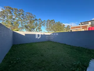 Parede lateral cinza e gramado verde de uma propriedade em Lajeado.