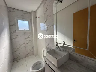 Banheiro com revestimento em mármore branco e louças brancas.