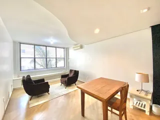 Sala de estar com móveis de madeira e grandes janelas.