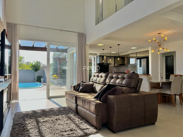 Sala de estar com sofá de couro marrom e acesso a uma área externa com piscina.