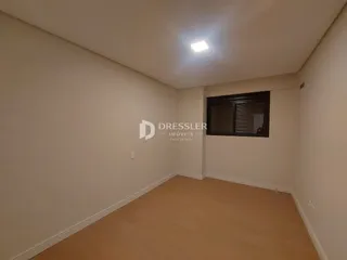 Ambiente interno de uma sala com piso de madeira clara e paredes brancas.