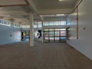 Vista de um corredor interno com piso de cerâmica e paredes brancas.
