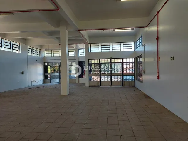Vista de um corredor interno com piso de cerâmica e paredes brancas.