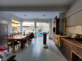Vista interna de uma sala de jantar com mesa de madeira e piso de cerâmica.