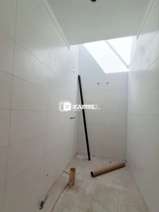 Foto de um corredor interno com teto inclinado e piso de concreto aparente.