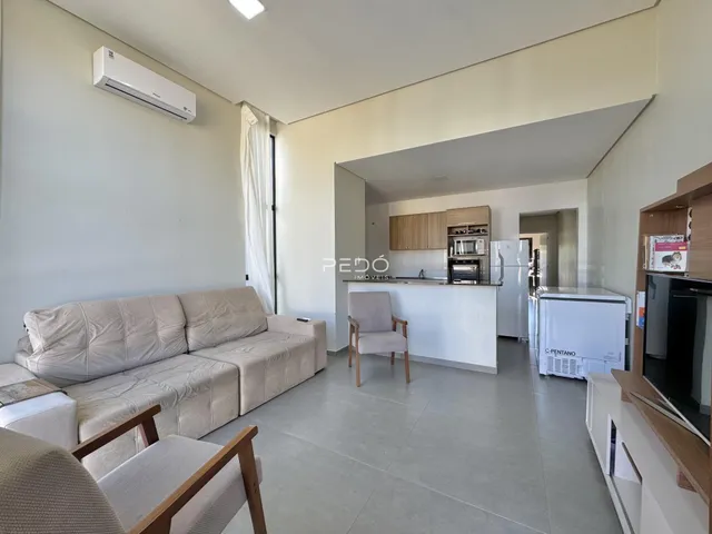 Sala de estar com sofá e vista para a cozinha em um imóvel no Brasil.