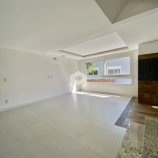 Sala ampla com piso claro e grande janela.