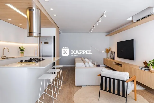 Sala de estar moderna com cozinha aberta e piso de madeira.