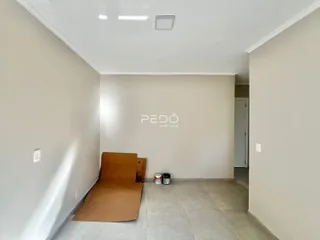 Um corredor interno com paredes brancas e piso de cerâmica.