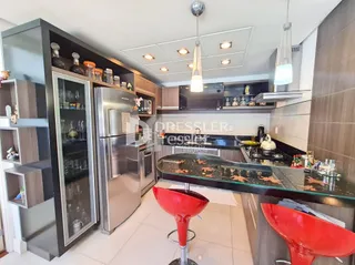Vista da cozinha moderna com armários escuros e eletrodomésticos de aço inoxidável.