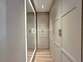 Corredor interno com armários embutidos e piso de madeira clara.