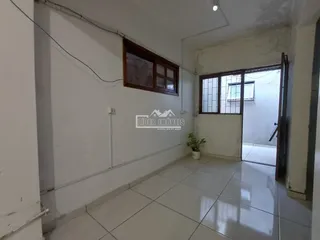Vista interna de um corredor com piso de cerâmica e janelas.