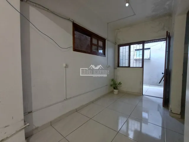 Vista interna de um corredor com piso de cerâmica e janelas.
