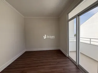 Sala de estar com piso de madeira e porta de vidro que dá para a varanda.