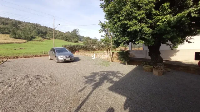 Vista da fachada de uma propriedade em Lajeado, Brasil, com uma estrada de acesso e vegetação ao fundo.