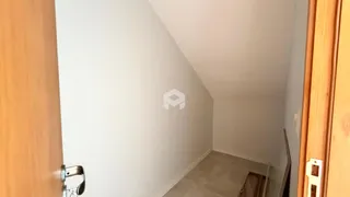 Corredor interno de uma residência com paredes brancas e piso claro.