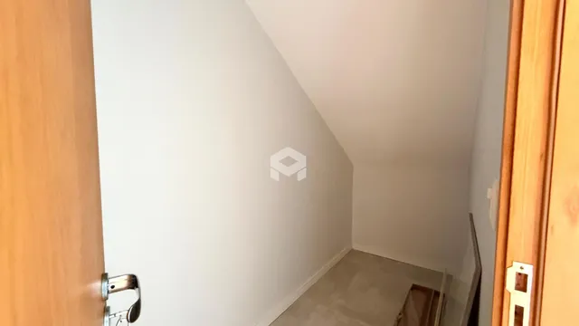 Corredor interno de uma residência com paredes brancas e piso claro.