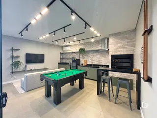 Sala de estar moderna com mesa de bilhar e cozinha integrada.