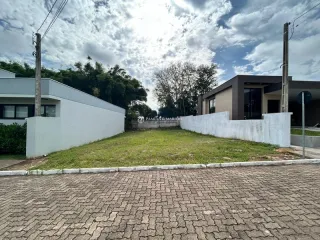 Fachada externa de uma residência com muro branco e área gramada.