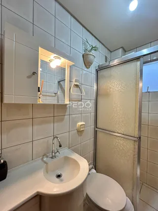 Foto de um banheiro com azulejos brancos e box de vidro.