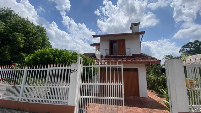 Fachada de uma casa com cerca branca e telhado de telhas no Brasil.