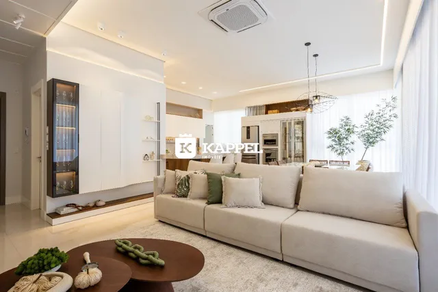 Sala de estar moderna com sofá grande e decoração clara em um apartamento.