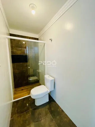 Foto de um banheiro com piso de madeira e divisória de vidro.