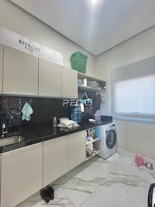 Uma cozinha com armários brancos e bancadas escuras em um imóvel.