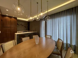 Uma sala de jantar com mesa de madeira e luminárias pendentes.