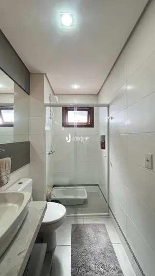 Foto de um banheiro com box de vidro e revestimento branco.