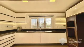 Vista da cozinha com armários brancos e bancadas escuras.