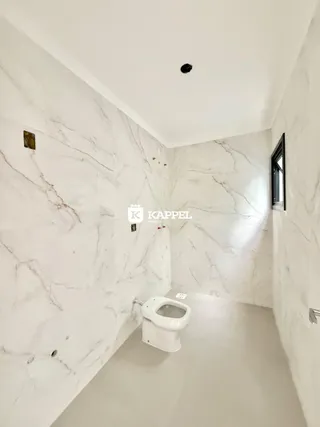 Banheiro com paredes de mármore branco e piso claro.