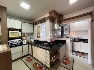 Cozinha com armários brancos e bancadas escuras em imóvel no Brasil.