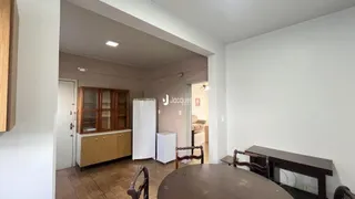 Interior de uma sala com armários de madeira e geladeira branca.