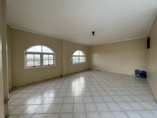 Vista interna de um ambiente com piso de cerâmica e duas janelas arqueadas.