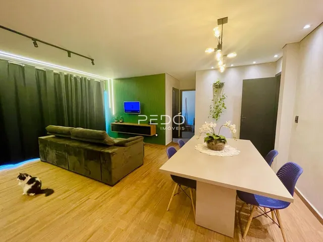 Sala de estar com piso de madeira e sofá verde em um apartamento.