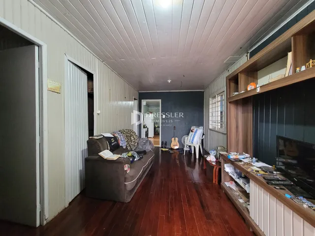 Interior de uma sala de estar com piso de madeira e móveis.