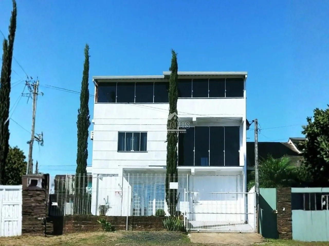 Fachada de uma residência em Lajeado, Brasil, com cerca e vegetação ao redor.