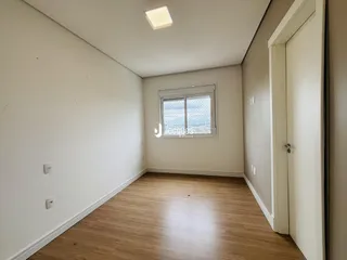 Vista interna de um ambiente com piso de madeira clara e paredes brancas.