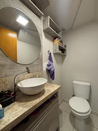 Banheiro moderno com bancada de granito e vaso sanitário.