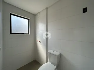 Foto de um banheiro interno com paredes brancas e azulejos.