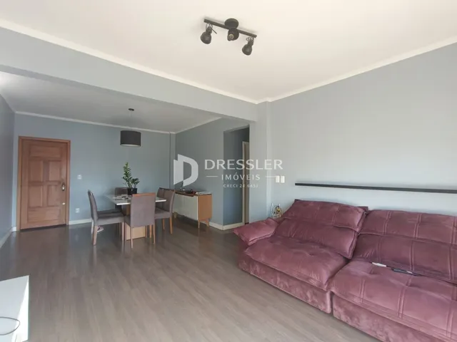Sala de estar com sofá e mesa de jantar em ambiente claro.
