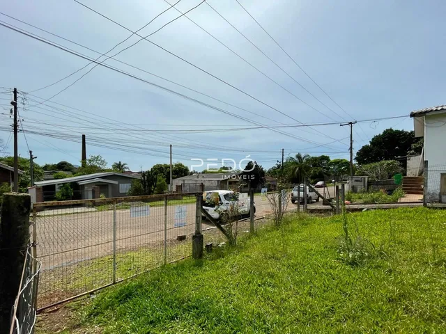 Vista externa da propriedade com cerca de arame e gramado.