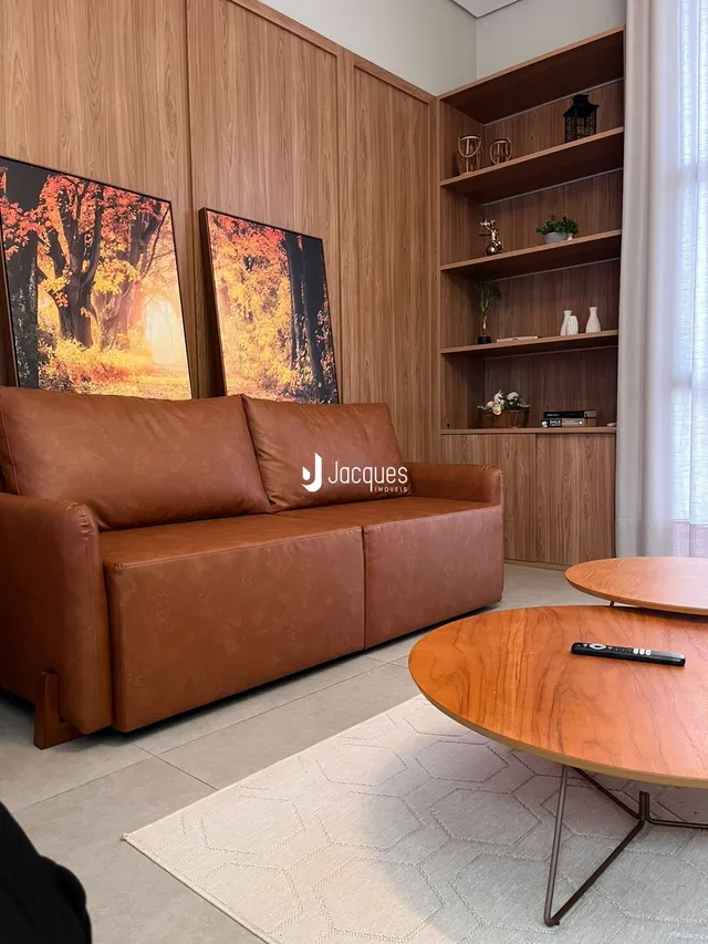 Sala de estar com sofá de couro marrom e painéis de madeira na decoração.