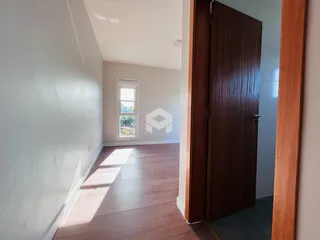 Corredor com piso de madeira e janela iluminada.