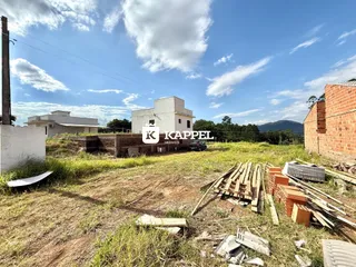 Vista externa de uma casa branca com terreno e materiais de construção no primeiro plano.