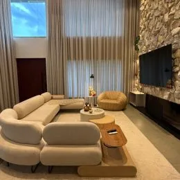 Sala de estar com sofás claros e cortinas brancas.