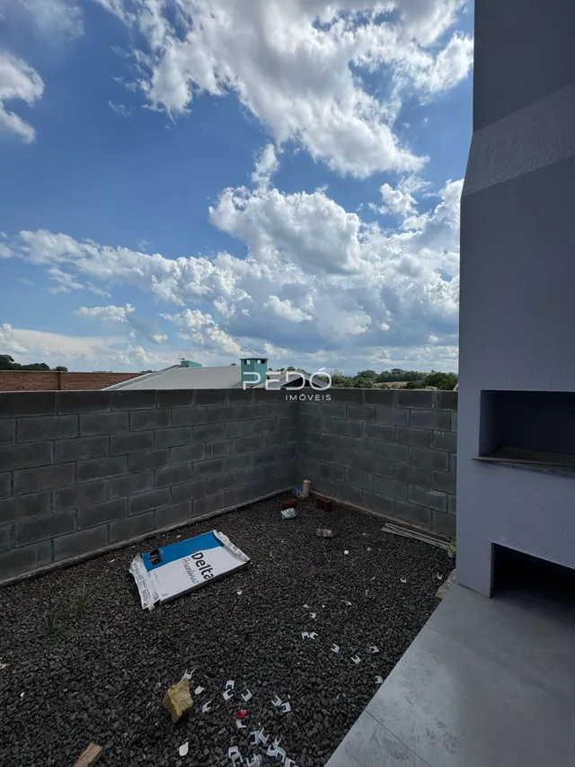 Área externa com muro de tijolos e piso de cascalho.