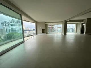 Vista ampla de um ambiente interno com grandes janelas que dão para um prédio.