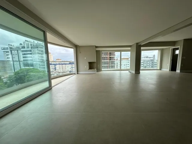 Vista ampla de um ambiente interno com grandes janelas que dão para um prédio.